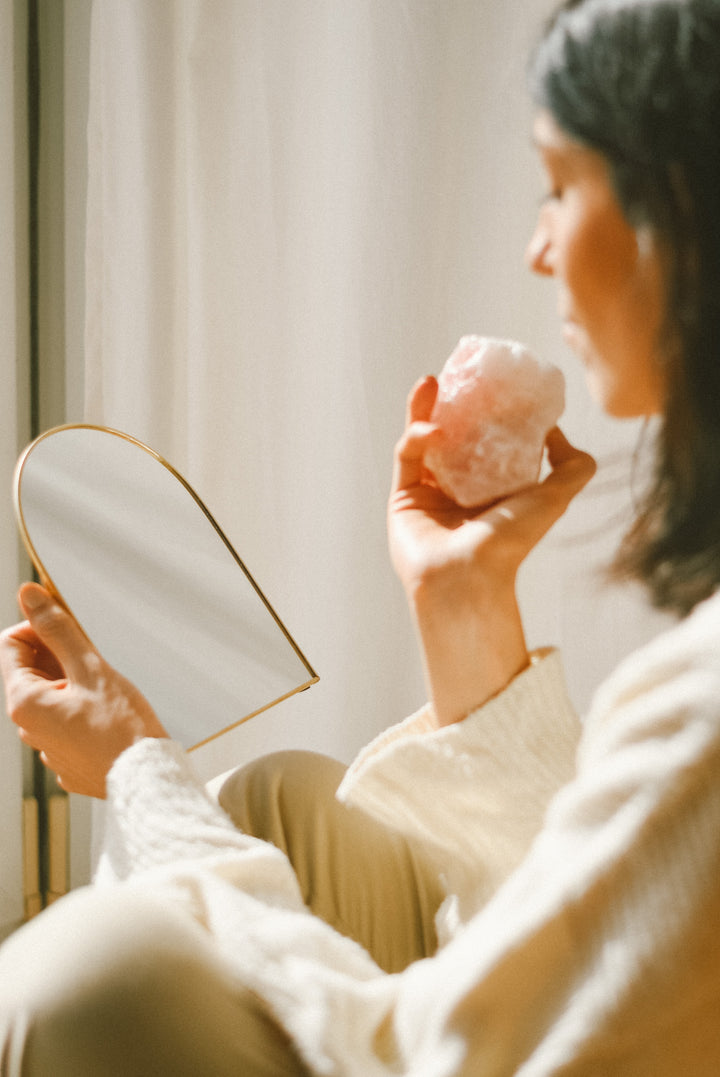 Verdevela: persona sujetando un cuarzo rosa en una mano y un espejo en la otra